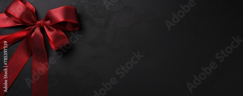 Red ribbon with bow on black background, Christmas card concept. Space for text. Red and Black Background