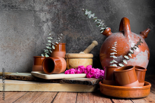 Bodegón con un viejo botijo, utensilios de madera y cerámica y flores de kalanchoe y ramas de eucalipto
