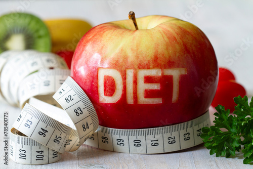 Red apple with cut-out word diet, measuring tape and fruits, diet and healthy lifestyle concept