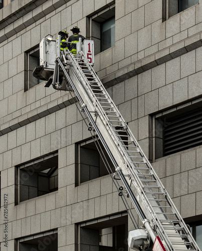 firefighters on a ladder against a building (unrecognizable, no face) FDNY new york fire fighters department on fire engine (emergency response agency) fireman photo