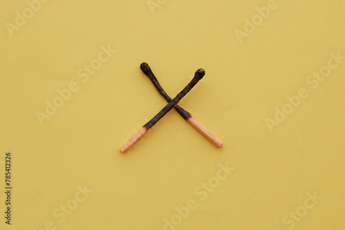Two crossed burnt matches on a yellow background, smoking ban, matches are not a toy, fire safety