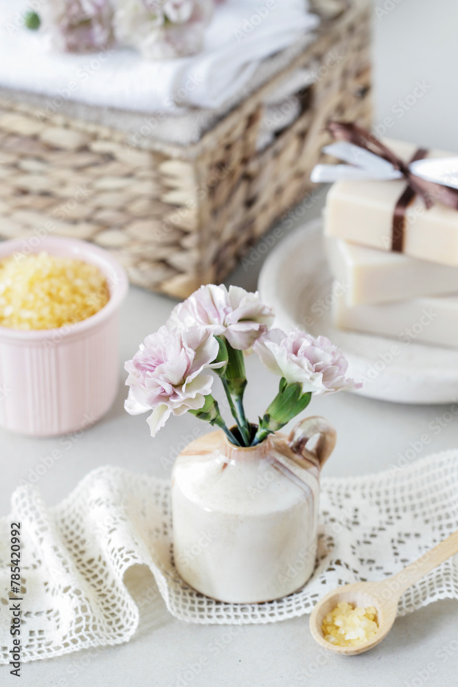 Bouquet of pink carnations and spa cosmetics on the table.