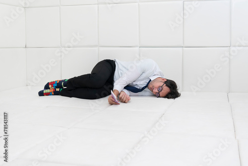 Sad and frustrated businessman in formal wear sitting in a white room in a mental hospital 