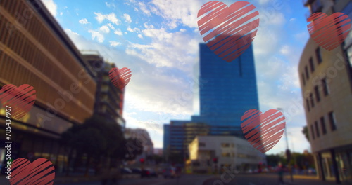 Image of red hearts falling over cityscape