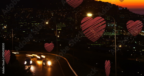 Image of red hearts falling over night cityscape