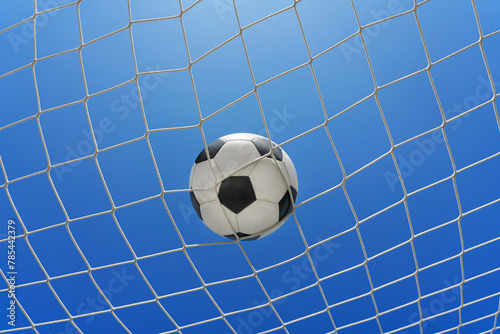  Soccer ball in soccer goal net in a big stadium isolated on blue sky. soccer net. © Igor Link