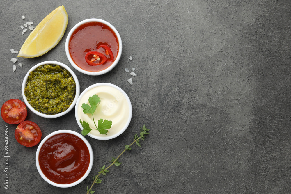 Different tasty sauces in bowls and ingredients on grey table, flat lay. Space for text Different tasty sauces in bowls and ingredients on grey table, flat lay. Space for text