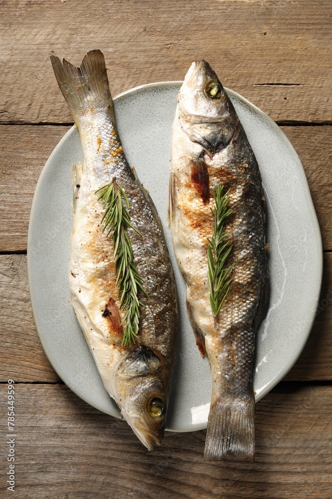 Delicious baked fish and rosemary on wooden table, top view Delicious baked fish and rosemary on wooden table, top view