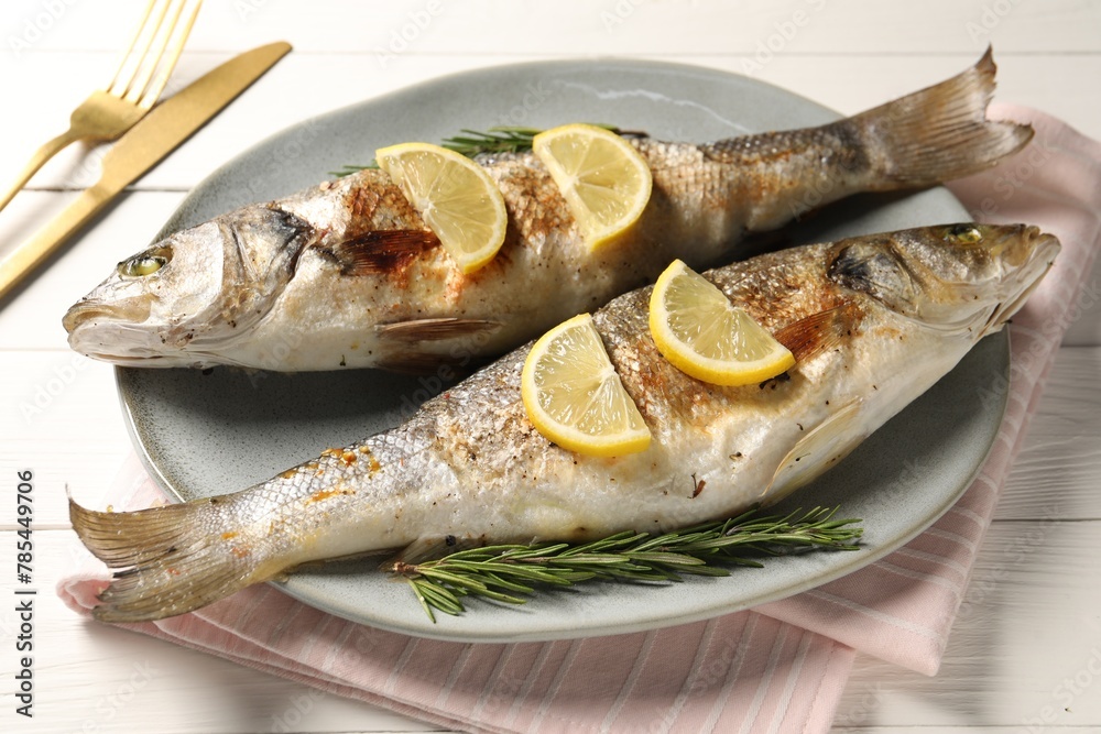 Delicious baked fish served on white wooden table