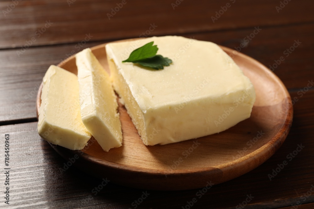 Cut tasty butter with parsley on wooden table