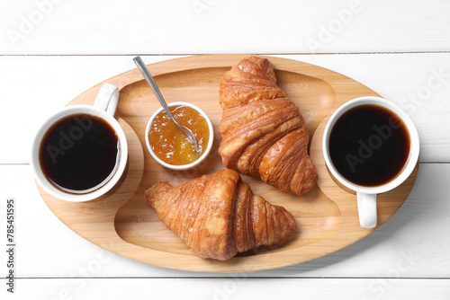 Fototapeta Naklejka Na Ścianę i Meble -  Tasty breakfast. Cups of coffee, jam and croissants on white wooden table, top view