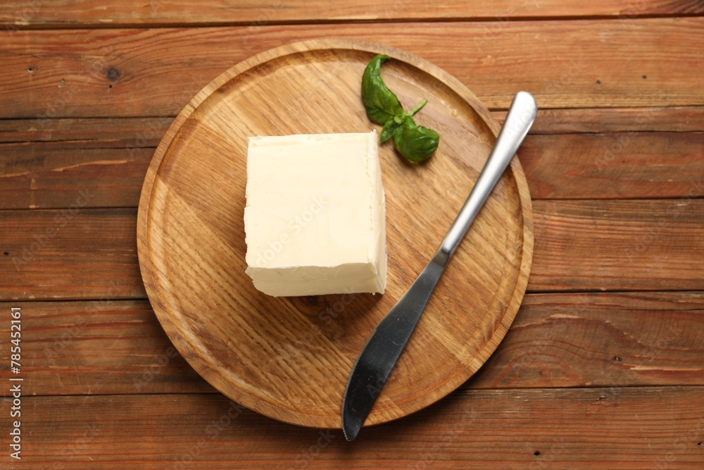 Block of tasty butter, knife and basil on wooden table, top view Block of tasty butter, knife and basil on wooden table, top view