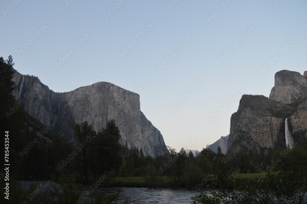 Lake with mountain and trees in the background with waterfall at sunset in Yosemite National Park