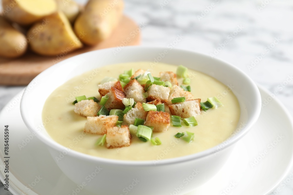 Tasty potato soup with croutons and green onion in bowl on white table, closeup Tasty potato soup with croutons and green onion in bowl on white table, closeup