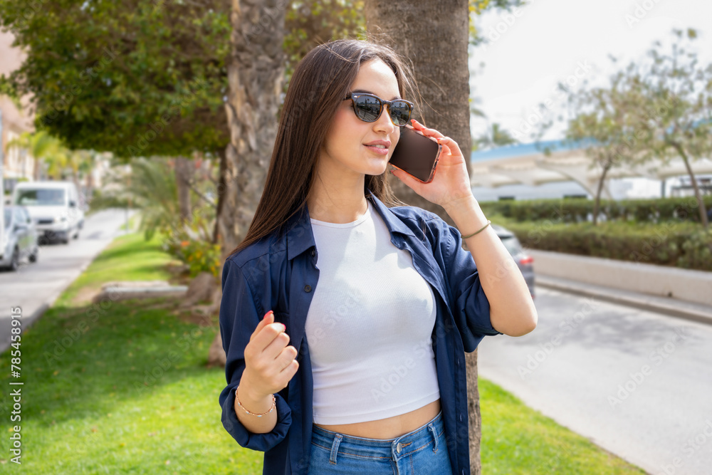 Young lady talking on the mobile phone outdoor.