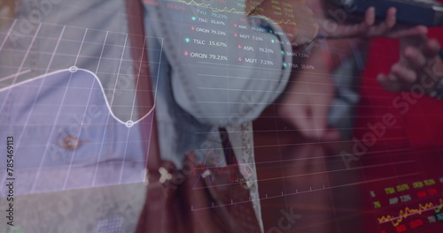 Image of trading board, graphs over midsection of woman inserting password on credit card reader