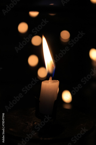 Close-up of the flame of candle in the dark in church with bokeh background. Candle light with copy space.