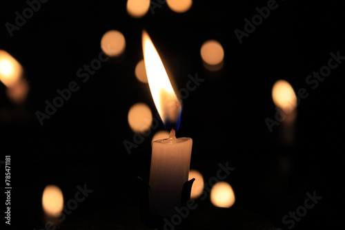 Close-up of the flame of candle in the dark in church with bokeh background. Candle light with copy space.