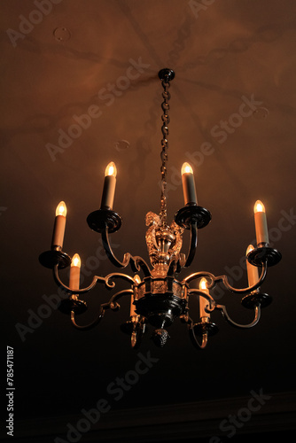 Golden antique chandelier hanging in church. Close-up of Classic crystal chandelier, luxury light lamp with dark brown background.