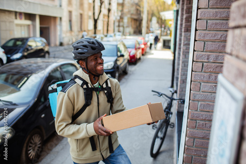 Happy delivery man with a package box on a city street