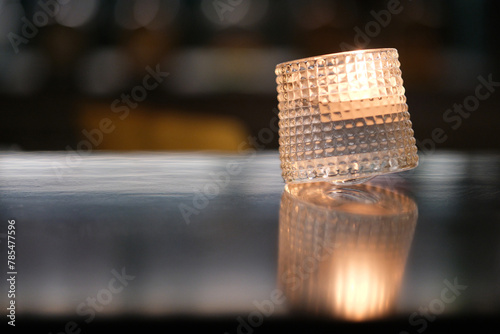 close up candle light in glass on bar counter with defocus bokeh at night