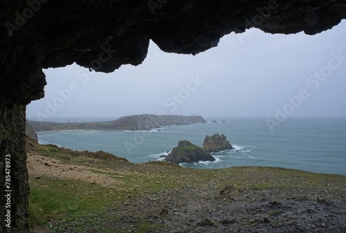 Coastline view from inside a bombed german Second World War bunker on Anse de Pen Hat, Brittany. Lighthouse. Cloudy spring day. Selective focus. photo