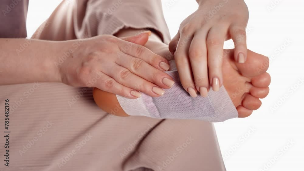 Female hands applying a self-adhesive medical pad on the forearm with care and precision Female hands applying a self-adhesive medical pad on the forearm with care and precision