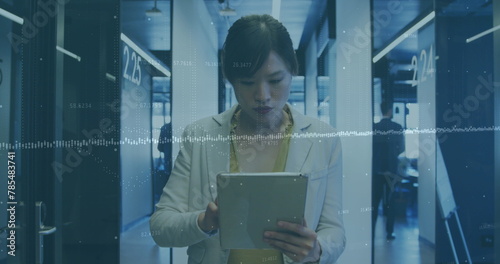 Image of financial data processing over asian businesswoman using tablet in office