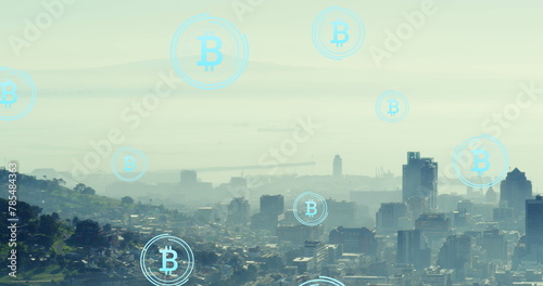 Image of bitcoin icons floating over aerial view of cityscape against cloudy sky