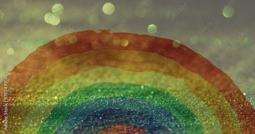 Fototapeta premium Image of hand painted rainbow over glowing sand falling in background