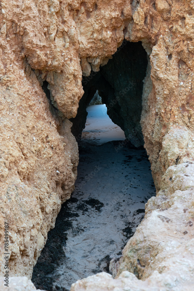 Obraz premium 3 Irmaos beach with an islet seen through a rock in the town of Alvor in the Algarve region