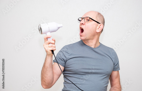 Bald Caucasian man uses a hair dryer.