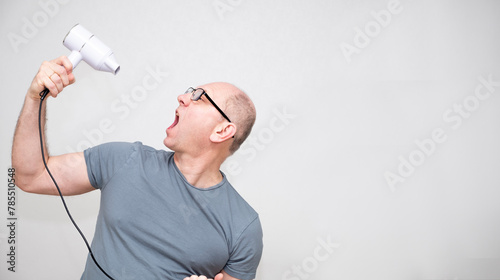 Bald Caucasian man, 50 years old, wearing glasses, uses a hair dryer, pretends to sing,