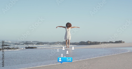 Image of stars over african american woman raising hands at beach
