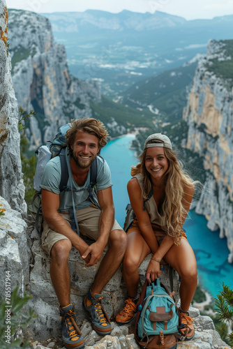 Energetic couple smiles atop steep peaks, enjoying extreme hiking adventures amidst stunning landscapes.