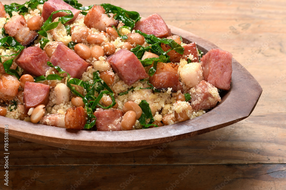 Feijão tropeiro in a wooden container, typical food from Minas Gerais, Brazil, wooden base 
