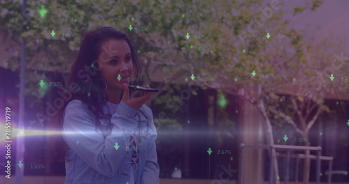 Image of green arrows and data processing over smiling biracial woman using smartphone outdoors