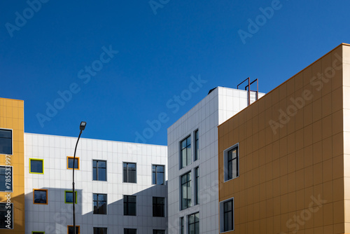 Fragment of complex of buildings of variable storey with windows of different sizes for articles, blogs, sites on construction, architectural theme. Modern technology of building facades design