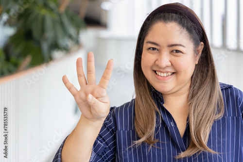 Happy smiling middle aged asian woman pointing up 4 fingers, four points, number four, forth point
