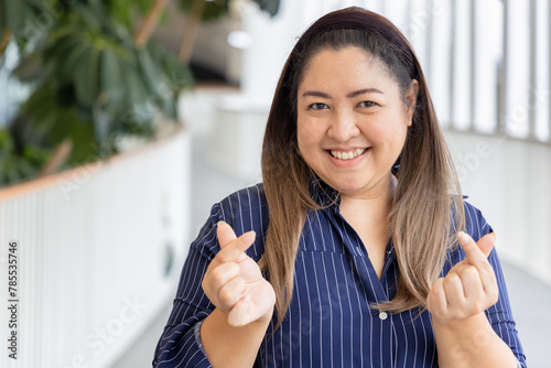 Friendly Happy Smiling Middle Aged Asian woman showing heart hand gesture, concept image for love, care, friendship