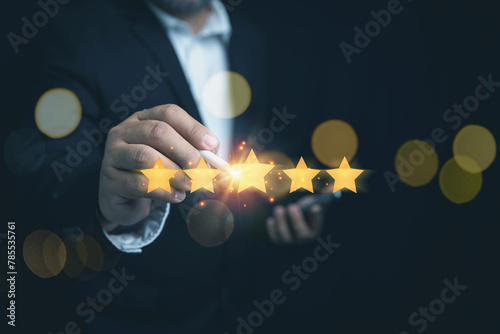 Customer satisfaction concept. Businessman touching five glowing golden stars for customer services excellence. Evaluation survey after client use product and service.