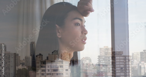 Image of cityscape over biracial woman looking through window