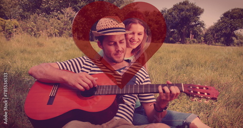 Image of red heart over couple in love with guitar