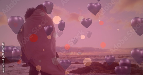 Image of purple hearts over couple in love by seaside