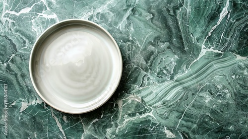 A top view of a white plate resting on a green marble surface, combining the simplicity of dining with the elegance of stone