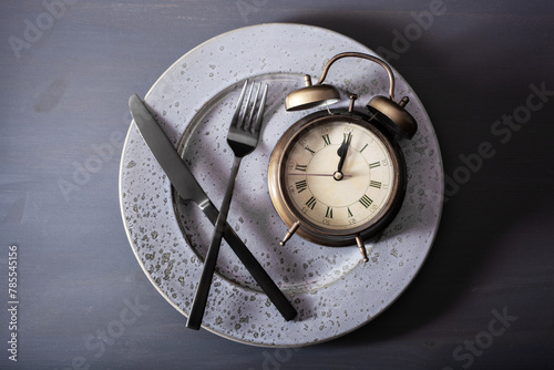 Obraz na płótnie concept of intermittent fasting, ketogenic diet, weight loss. fork and knife, alarmclock on plate w salonie