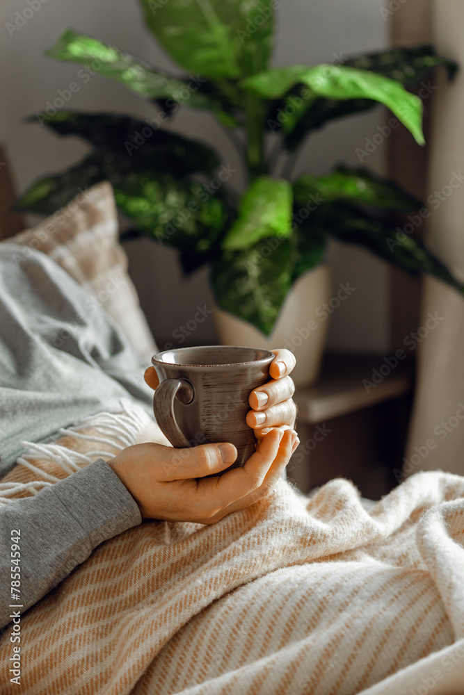 a caucasian man relaxing at home, drinking coffee in bed under blanket