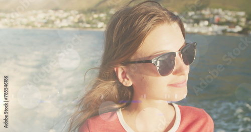 Image of bokeh over caucasian teenager girl wearing glasses and sailing
