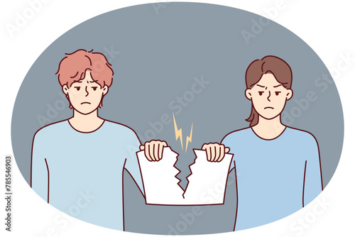 Angry man and woman holding sheet tearing joint paper after quarrel or family disagreement. Guy and girl with hatred in their eyes tear document confirming marriage
