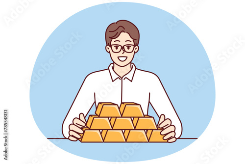 Businessman with gold bars sitting at table and smiling looking at camera for precious metals investment. Man investor with gold bars avoiding inflation and symbolizing diversification of assets
